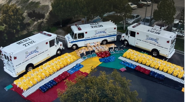 Aerial overhead view of three Medix Major Incident and Disaster Response Units with hundreds of pieces of color-coded medical equipment and supplies laid out in formation in the parking lot